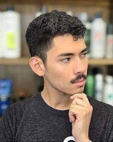 Men's textured curly cut with a defined taper and shaped mustache