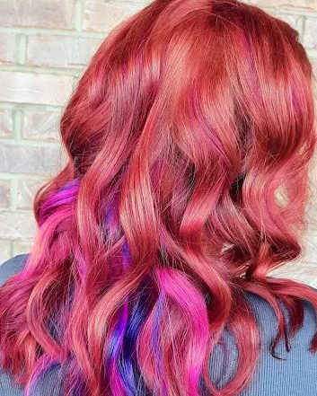 Vivid red hair with pink and purple peekaboo color, loosely waved