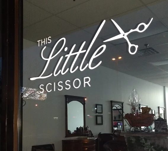 The This Little Scissor storefront window with the script logo etched on the glass